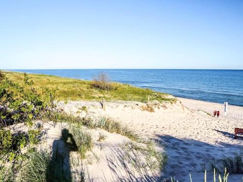 a sandy beach with a bench and the ocean at 2 person holiday home in Højer in Højer