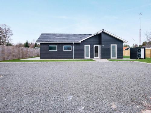 a black house with a driveway in front of it at 16 person holiday home in Glesborg in Glesborg