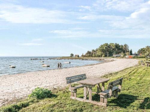 a picnic table and benches on a beach at 6 person holiday home in Kolind-By Traum in Kolind