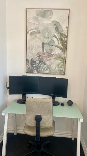 a desk with a computer monitor and a chair at Picture Perfect in the heart of the Village in Greytown
