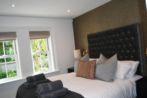 a bedroom with a large bed and two windows at Luxury Croft Templepatrick Near Airport Rabbit and Hilton hotel in Templepatrick