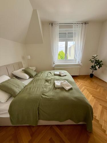 a bedroom with a large green bed with a window at Family Villa Hanspaulka in Prague