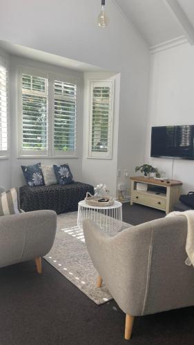 a living room with two couches and a tv at Picture Perfect in the heart of the Village in Greytown
