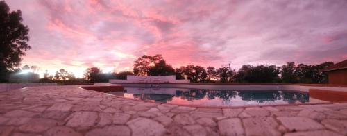 a sunset over a swimming pool in a yard at Casa de Campo - Haras in Elizade