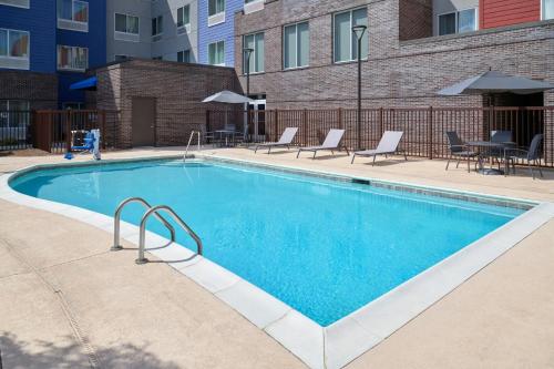 a swimming pool with chairs and a table and a building at Residence Inn by Marriott Charlotte Airport in Charlotte