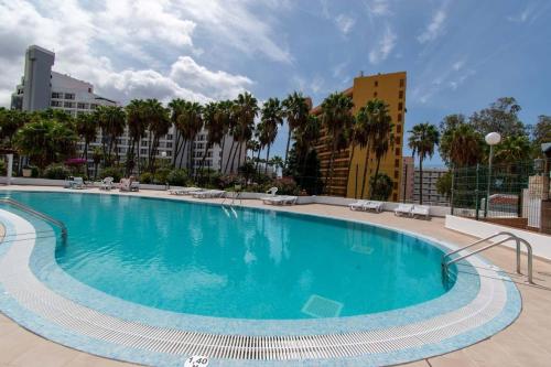 Una gran piscina con palmeras y edificios. en Modern 3 Bedroom Villa Jaccuzi, en Playa Fañabe