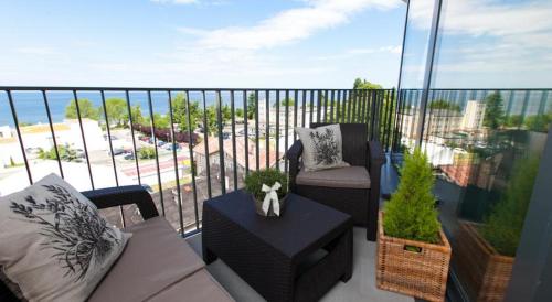 a balcony with a couch and a chair and a table at Horyzont Luksusowe apartamenty nad morzem z parkingiem Międzyzdroje in Międzyzdroje