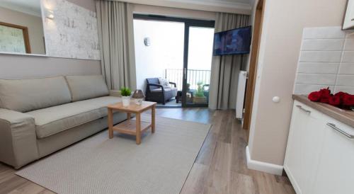 a living room with a couch and a table at Horyzont Luksusowe apartamenty nad morzem z parkingiem Międzyzdroje in Międzyzdroje
