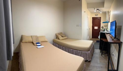 a small room with a bed and a desk with a computer at SplashNStay in Puting Kahoy