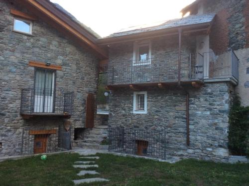ein Steinhaus mit einem Balkon und einem Hof in der Unterkunft Chez Sylvie Vda-Issogne-001 in Issogne