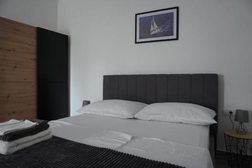 a bedroom with a white bed with a black headboard at Apartments and rooms with WiFi Sibenik - 24424 in Šibenik