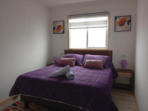 a bedroom with a purple bed with a window at Depto Ensueño Patagonia in Puerto Natales