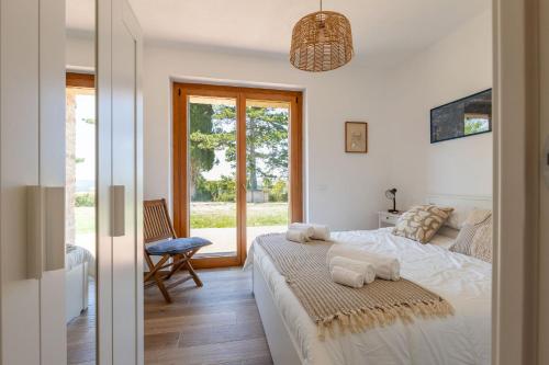 a white bedroom with a bed and a window at Italian Experience- Poggio Padule in San Venanzo