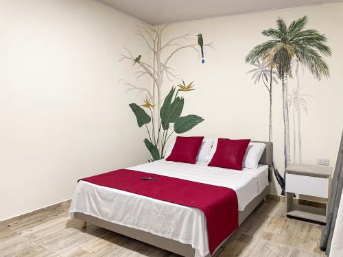 a bedroom with a bed with red pillows and palm trees at Best View Aparta Hotel in Dosquebradas