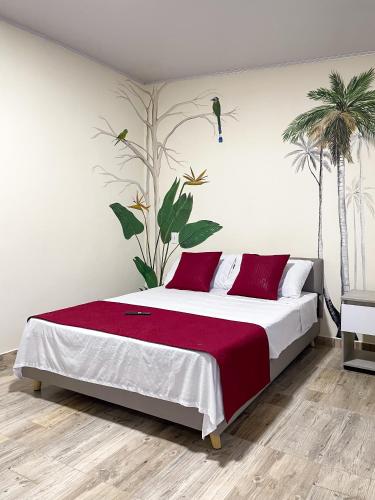 a bedroom with a large bed with red pillows and palm trees at Best View Aparta Hotel in Dosquebradas