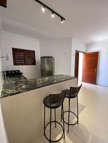 a kitchen with two bar stools and a counter at Apartamento Alto de São Manoel in Mossoró