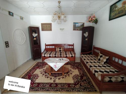 ein Wohnzimmer mit zwei Betten und einem Tisch in der Unterkunft maison de baraka in Al Ḩārah al Kabīrah