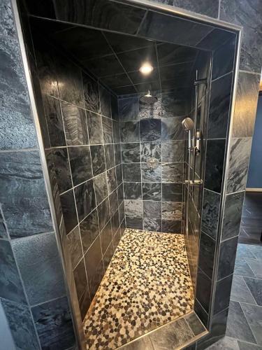 a bathroom with a shower with black tile at Southview Lodge in Valemount