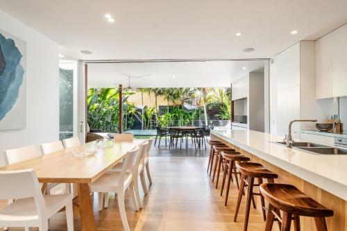 an open kitchen and dining room with a long table and chairs at Alpha Luxe - Pet Friendly Luxury Home and Heated Pool in Byron Bay