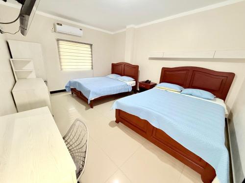 a bedroom with two beds and a chair in it at Hotel SMIR, Huaquillas in Huaquillas