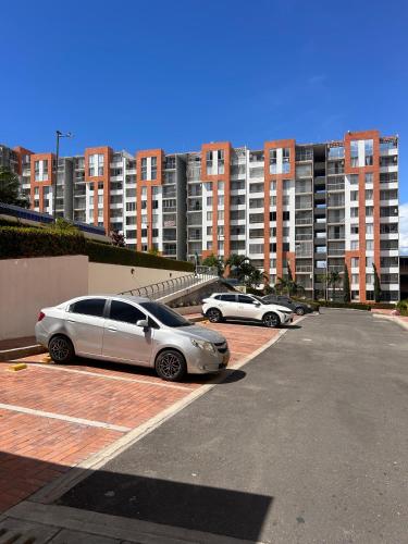 two cars parked in a parking lot with tall buildings at Espectacular Apartamento vía el Peñón in Girardot