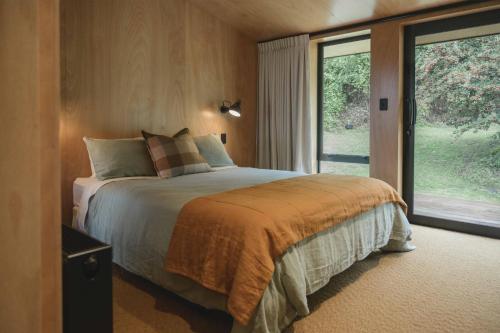 a bedroom with a bed and a large window at Lakefront Luxury at Okere Falls Lake Rotoiti in Rotorua