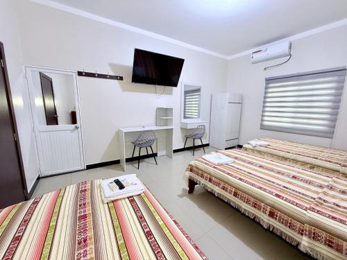 a hotel room with two beds and a desk at Hotel SMIR, Huaquillas in Huaquillas