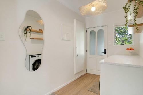 a white kitchen with a washing machine in the wall at Luxe Country Escape in Ramarama
