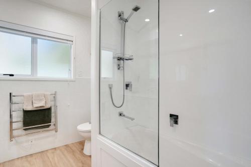 a white bathroom with a shower and a toilet at Luxe Country Escape in Ramarama