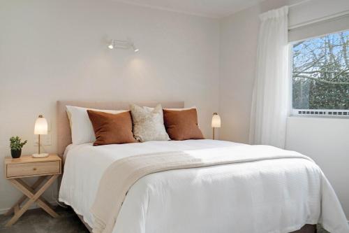 a white bedroom with a white bed and a window at Luxe Country Escape in Ramarama