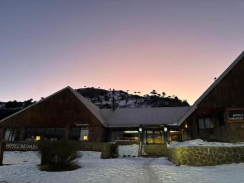 un edificio con nieve en el suelo delante de él en Hotel Amarilla, en Caviahue