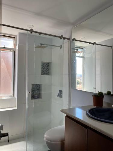 a bathroom with a toilet and a glass shower at Bogotá Urban Suites in Bogotá