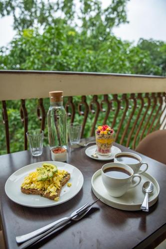 a table with two plates of food and a cup of coffee at The Palm House in Canacona