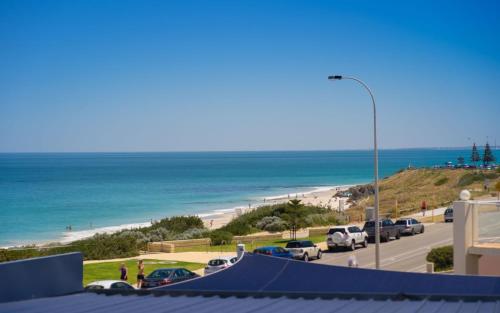 a view of a beach with cars parked on the road at Cottesloe Blue Apartment in Perth