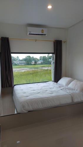 a bedroom with a large window in an rv at Buketree homestay satun in Ban Khok