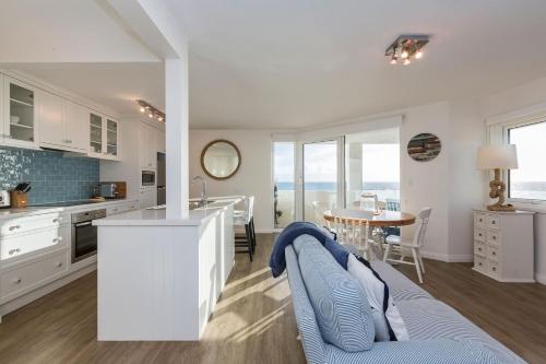 a kitchen and living room with a table and a counter at Cottesloe Blue Apartment in Perth