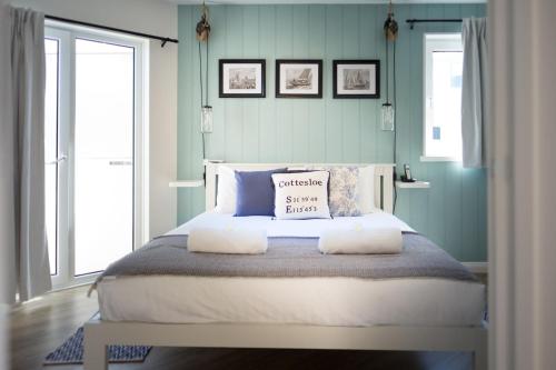 a bedroom with a large bed with two windows at Cottesloe Blue Apartment in Perth