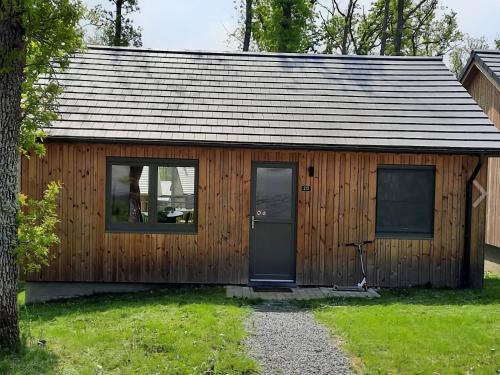 a wooden cabin with a door and a window at Cosy chalet near Durbuy in nature in Somme-Leuze