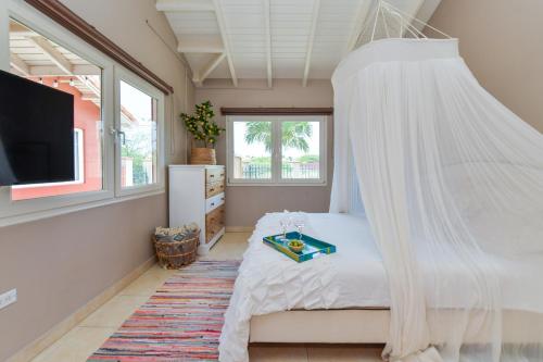 a bedroom with a bed with a canopy at Moderne studio Sun dichtbij de zee met zwembad in Oranjestad
