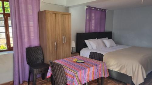 1 dormitorio con cama, mesa y cortinas moradas en Relaxing small cottage in nature, en Huayllabamba