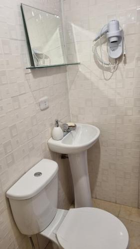 a white bathroom with a toilet and a sink at Cottage in nature in Sacred Valley with mountain views in Huayllabamba