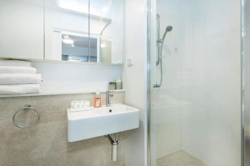 a white bathroom with a sink and a shower at Scarborough Pearl Apartment in Perth