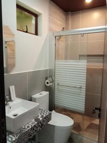 a bathroom with a toilet and a sink and a shower at Bugnaw Si-e Beach Resort in Anda