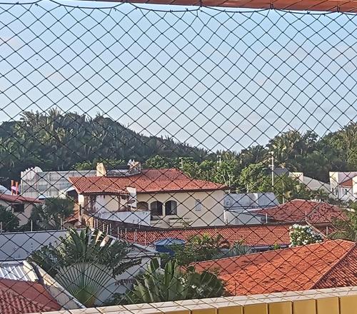 a view through a wire fence of roofs at Apê Aconchego Calhau - 3 Minutos de Carro da Praia in São Luís