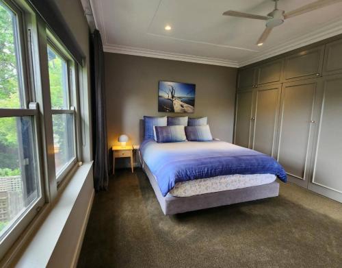 a bedroom with a bed with blue sheets and windows at Family Luxury In Lake Wendouree in Wendouree