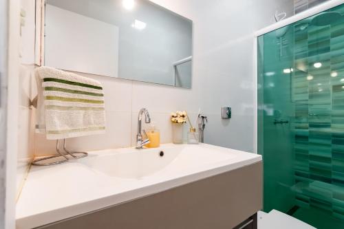 a bathroom with a sink and a glass shower at Loft 03 - Zona Sul Prox UMC, Pátio Vinhedos e Shopping in Uberlândia
