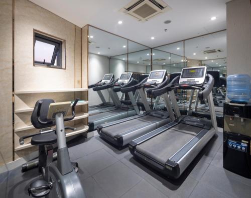 a gym with rows of treadmills and elliptical machines at Winsuites Saigon Hotel in Ho Chi Minh City