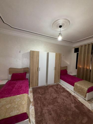 a bedroom with two beds with pink sheets at شقة كبيرة فيها 3 غرف و صالون مطبخ حمام و في شارع راقي في طنجة دار تونسي in Tangier