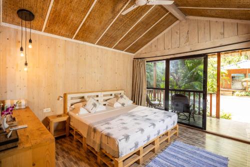 a bedroom with a bed and a large window at Palm Forest Palolem in Palolem