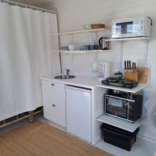 a small kitchen with white cabinets and a sink at Gästhus öppen planlösning in Oskarshamn